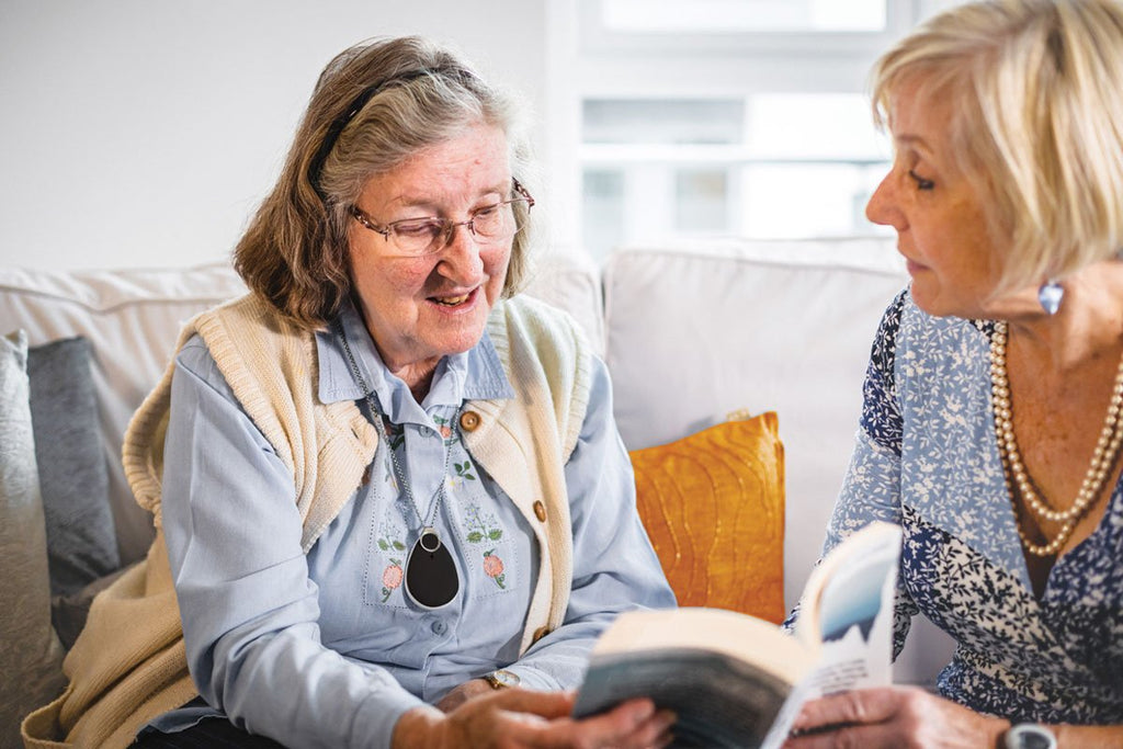 Elderly friends looking at a personal alarm