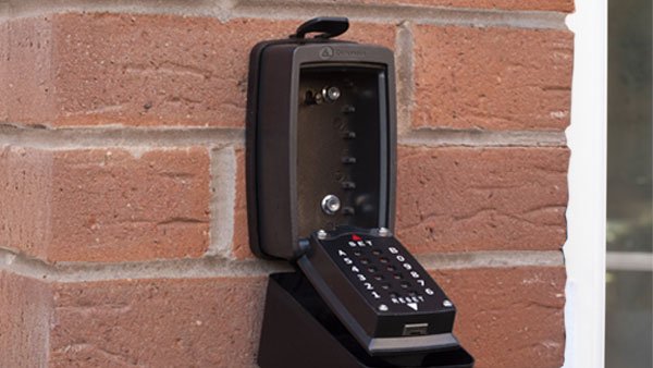 Black outdoor security keypad mounted on a brick wall